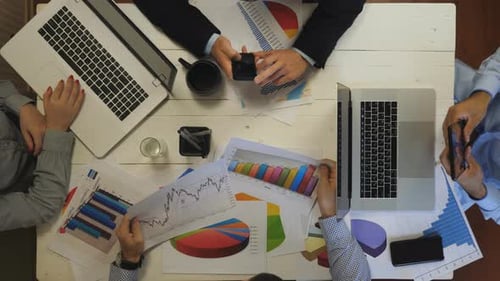 Top View to Male and Female Arms of Coworkers Plan a Future Project Sitting at Table