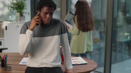 Man Talking on Phone Leaning on Office Table
