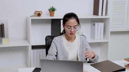Woman working at computer on desk with paper