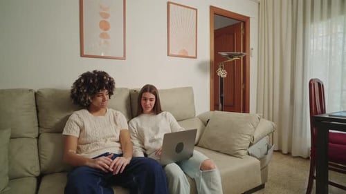 Two Friends Use Laptop on Couch