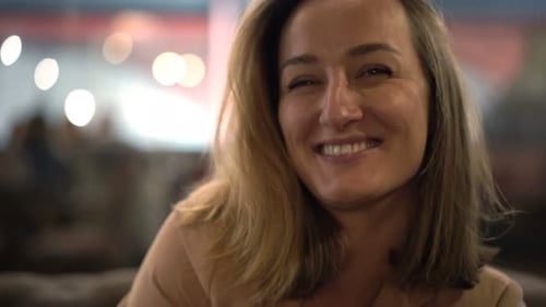 Portrait of Happy, Pretty Woman Sitting in Cafe at Night Alone