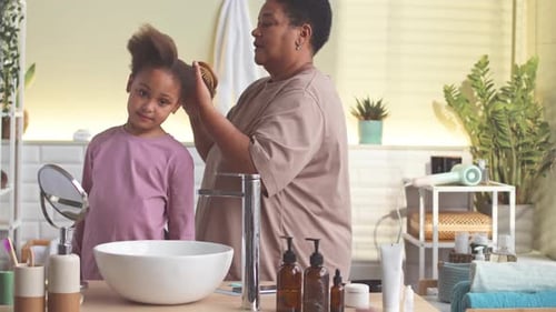 Woman Brushing Child's Hair in Bathroom