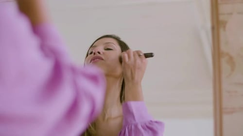 Woman Applying Makeup in Front of Mirror