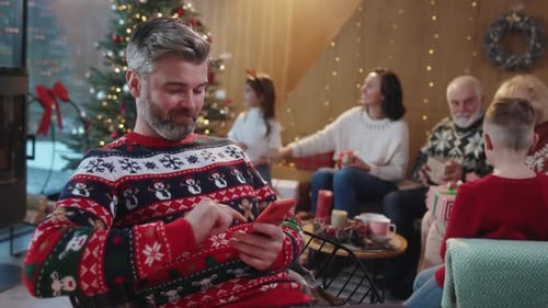 Man Using Phone at Christmas With Family