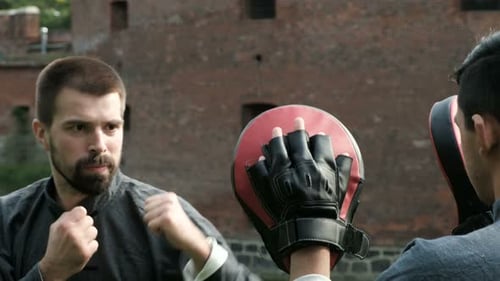 Two men practice martial arts sparring in city