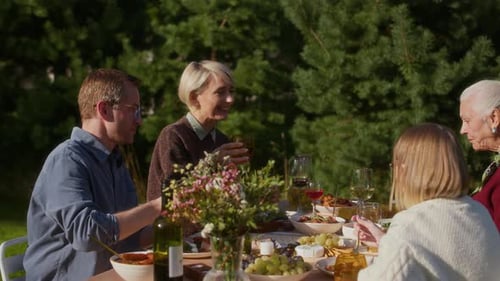 Family Gathered at Outdoor Table Toasting Drinks