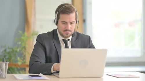 Businessman with Headset Working on Laptop