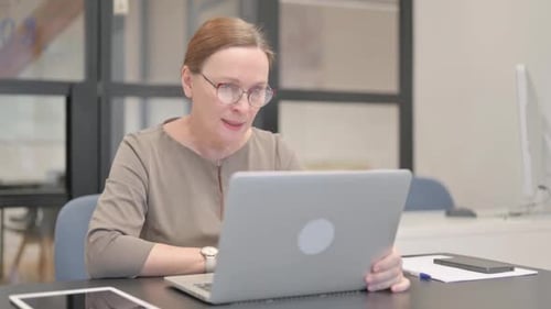 Woman Celebrates Success with Laptop in Office