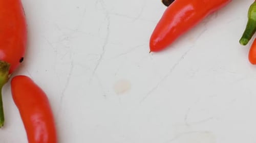 Slow panning shot of some fresh red chili peppers laying in a white bowl, close up.