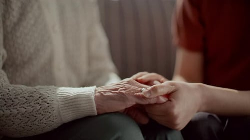 Nahaufnahme einer fürsorglichen Frau, die die Hände einer älteren Großmutter hält