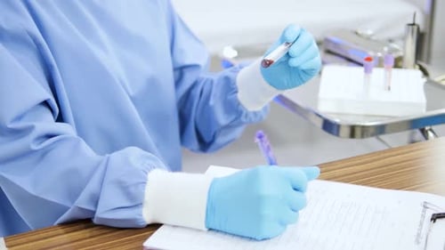 Close-up of an Asian female doctor writing a list of blood test results.