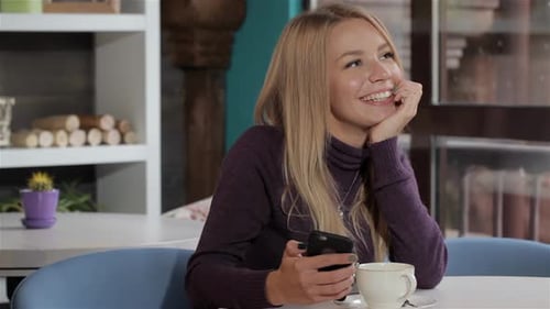 Woman Dreaming with Smartphone in Her Hand at the Cafe