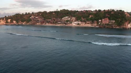 Cinematic forwarding drone to Bingin resort beach to film amazing tropical sunset beach with surfers