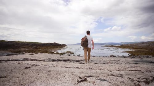 The Travel Lifestyle Concept Comes to Life As a Man Strolls Alone on a Sandy Beach Surrounded By the