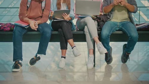 Legs of Students Sitting on the Bench in University HallWay During Break