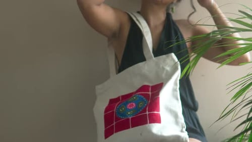 Mujer que sostiene una bolsa de lona blanca con un colorido diseño bordado, que representa la moda casual