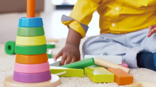 Cute infant playing with colorful toy blocks indoors