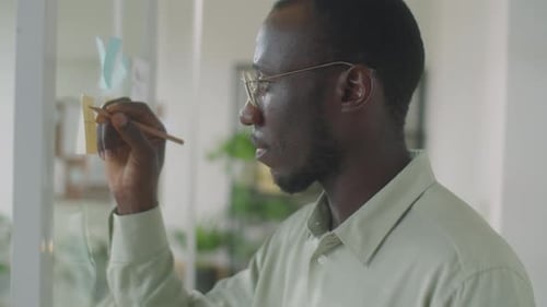 Man Writing on Glass Wall in Office