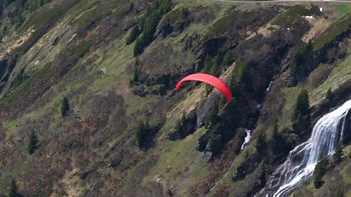 Paragliding approaching a waterfall in the mountains