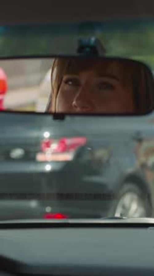 Reflection of Woman in Rear View Mirror on Windshield in Car