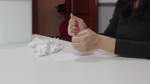 Woman crumples and discards paper at a desk