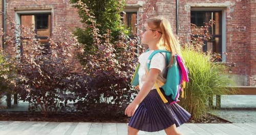 Rear view of schoolgirl goes to school in morning, pupil rushes to classes. Back to school