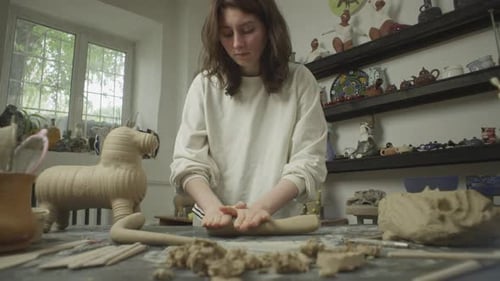 A Woman Ceramist Works with Clay on a Workbench in a Workshop