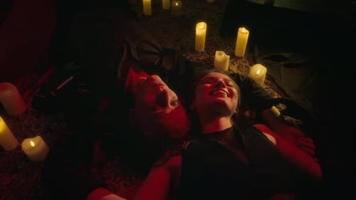Two Joyfully Smiling Vampires Lying Amidst Circle of Glowing Candles