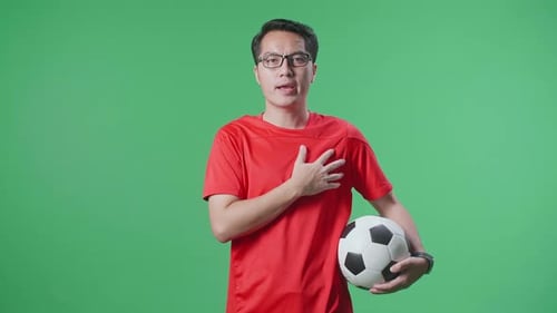 Asian Man With A Ball Singing National Anthem While Cheering Soccer On Green Screen Background