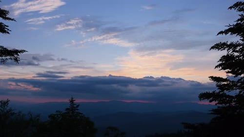 Zeitraffer des Sonnenuntergangs über majestätischen Bergen mit leuchtenden Wolken