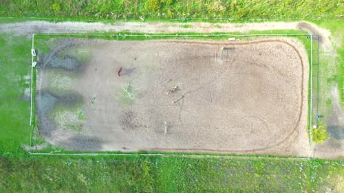 Aerial view of three horsemen. A riding field with fence and obstacles to train horses. In this spor