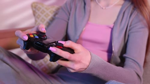 Teenage girl with controller playing video game on sofa at home, closeup