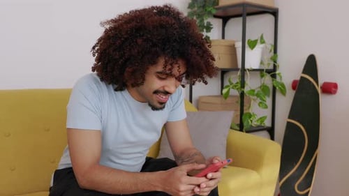 Man Sitting on Couch Using Mobile Phone Indoors