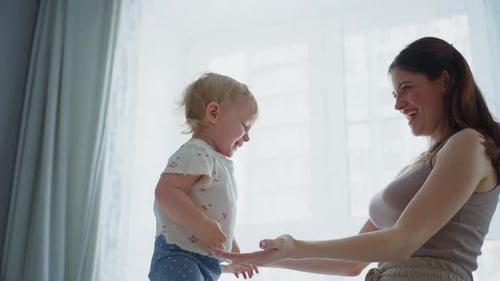 Woman Lifts Child Up And Down Playfully Indoors