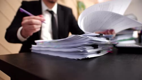 Closeup Stack of Office Documents in Which an Office Worker or Male Manager Writes Something