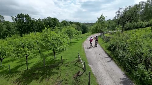 Two mountain bikers ride bicycles with beautiful nature around them. Drone shot in slow motion