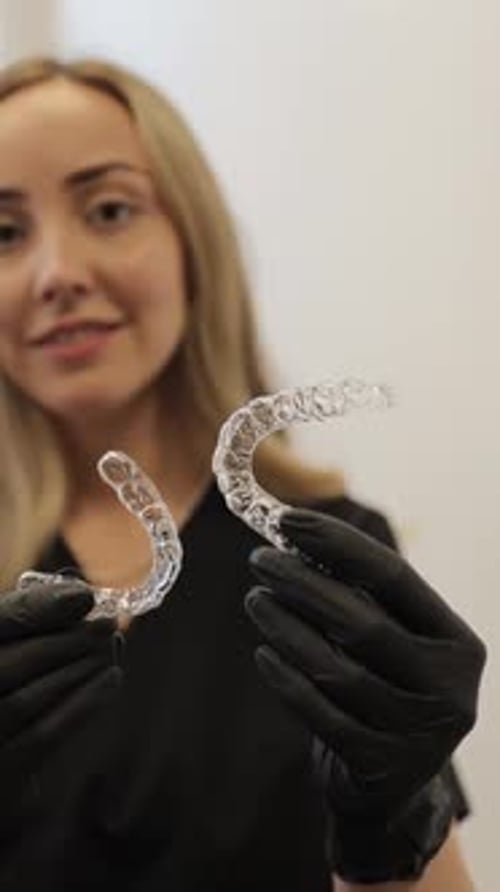 Woman Showing Clear Dental Aligners in Clinic