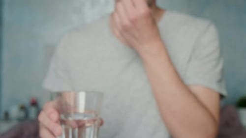 Man Takes Pill with Water Close Up