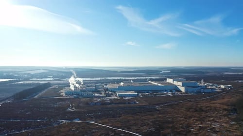 Industrial factory in environment under blue sky. Manufacturing among nature in winter.