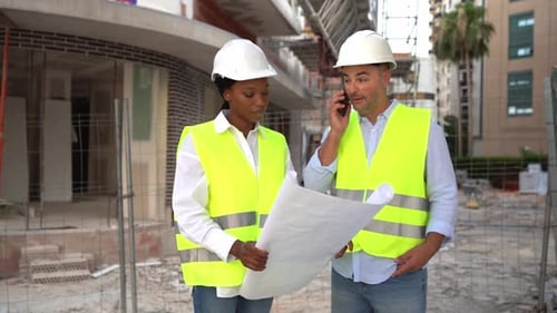 Construction Workers Reviewing Blueprints at Construction Site
