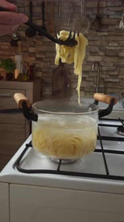 Fettuccine being cooked in boiling water on stove