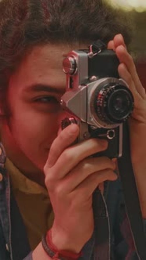 Vertical of Happy Gen Z Guy Taking Souvenir Photo in Neon Lit Cafe