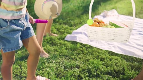 The Family Spreads a White Blanket on the Green Grass Setting Up Their Picnic Spot Under the Sunny