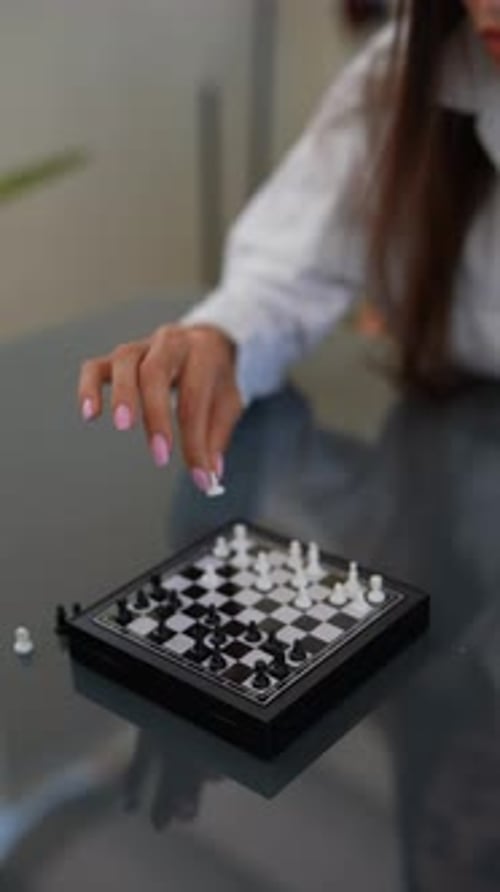 The Woman Exhibits Concentration and Strategic Thinking While Playing Mini Chess on a Glass Board
