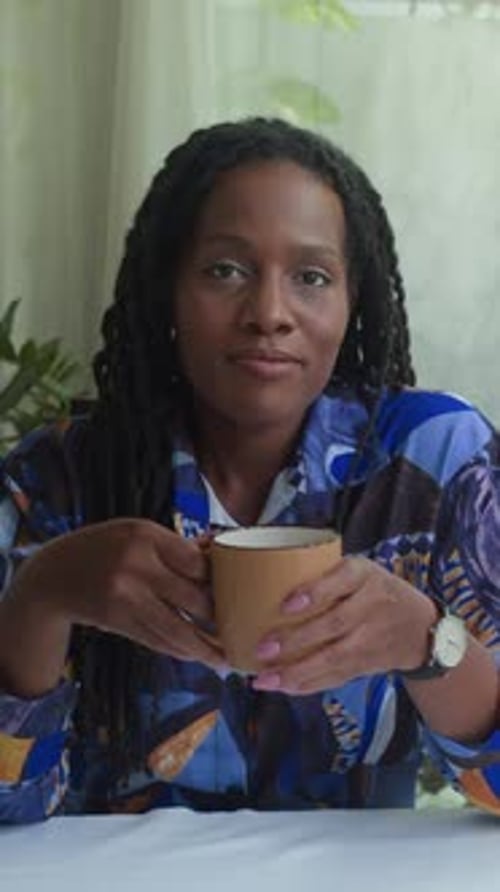 Woman Enjoying Coffee and Smiling at the Camera