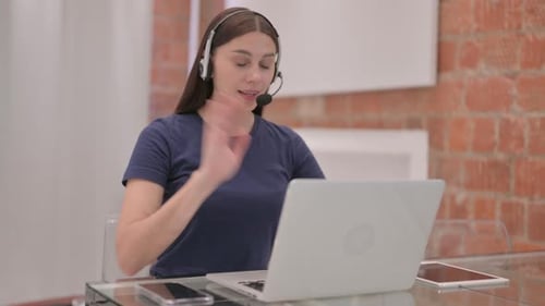 Young Woman Using Laptop with Headset at Desk