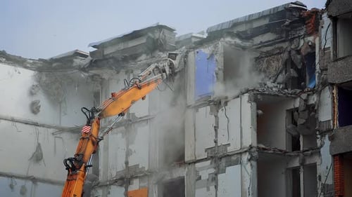 Excavator destroying demolished building. Breaking down old big house.