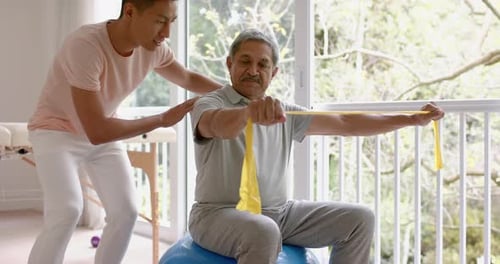 Physical Therapist Assists Senior Man with Exercise
