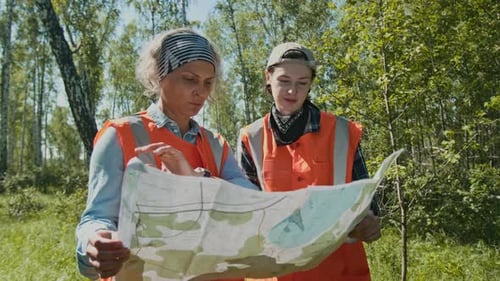 Two People Study Map in Sunny Field