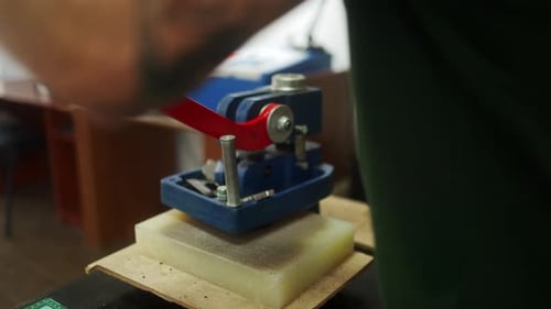 Close Up Shot of Professional Leather Craftsman Stands at Work Table and Uses Diecutting Press Man